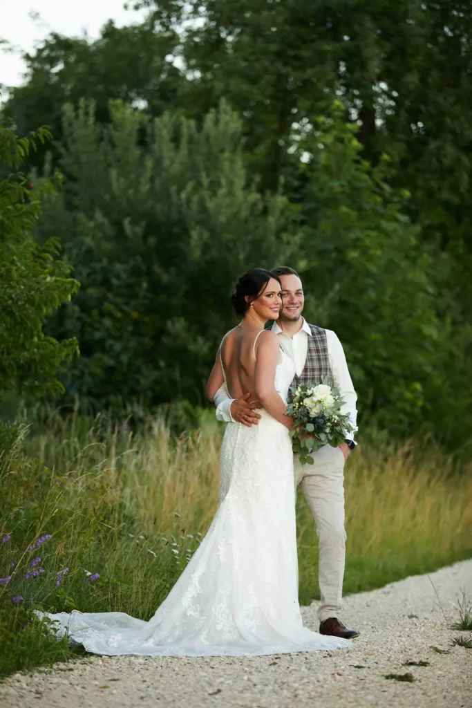 Portrait eines glücklichen Brautpaares auf einem asphaltierten Weg umgeben von Bäumen und Gebüsch. Perfekte Erinnerung für Verlobte, die auf der Suche nach den besten Hochzeitsfotografen sind.