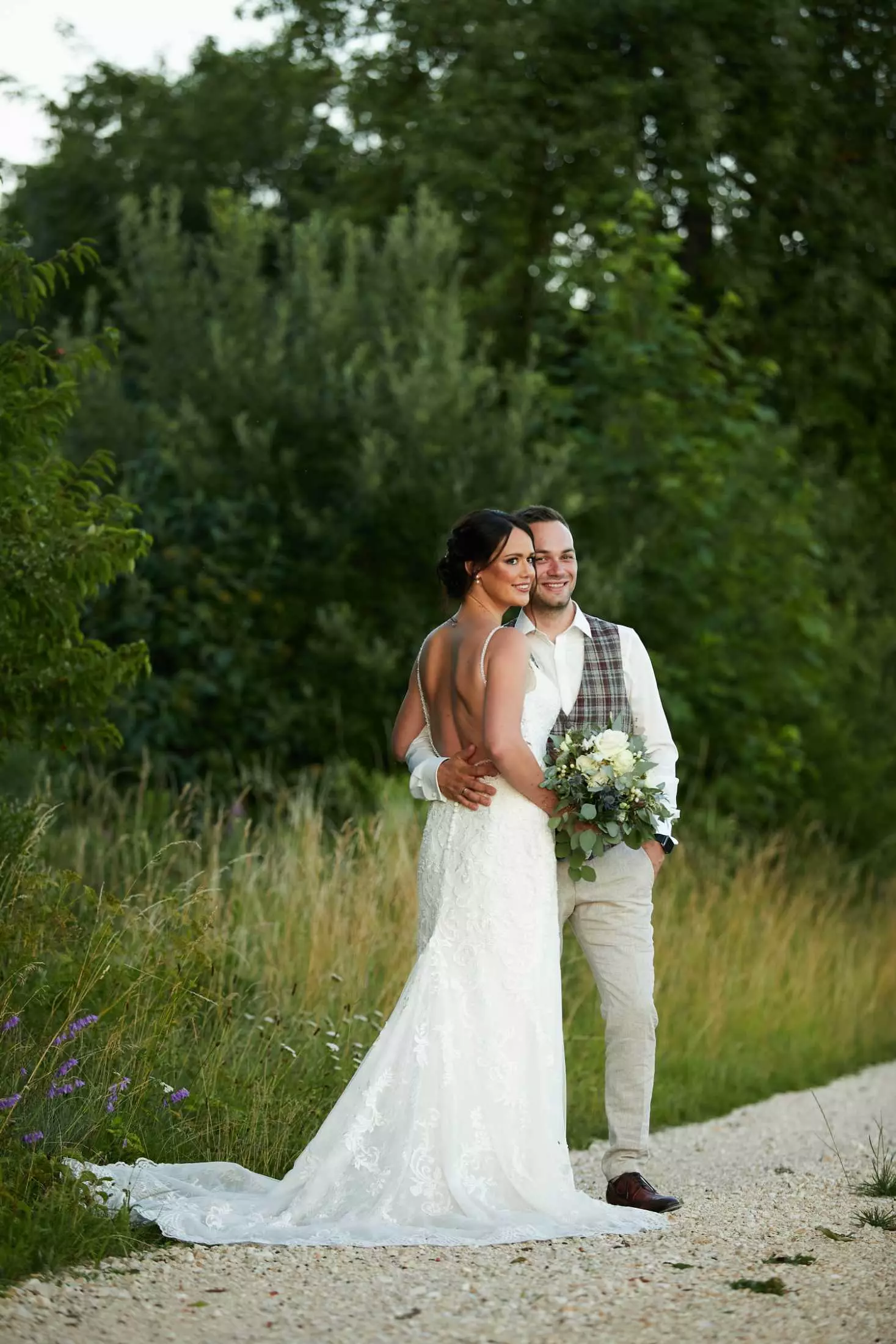 Hochzeitsfotograf Stuttgart | Portrait eines glücklichen Brautpaares auf einem asphaltierten Weg umgeben von Bäumen und Gebüsch. Perfekte Erinnerung für Verlobte, die auf der Suche nach den besten Hochzeitsfotografen sind.